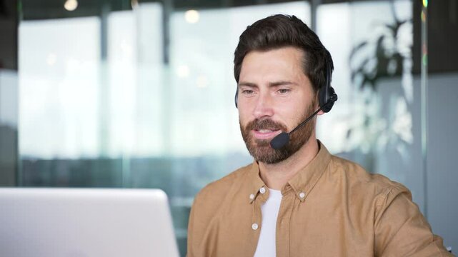 Corporate operator who works in customer support speaks on a video call using a laptop. Call center agent in wireless headset helping customer with complaints in office. Online consultation. Close up