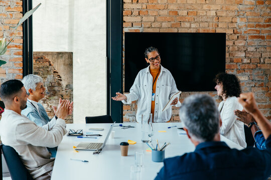Multicultural business team in a meeting celebrating success with applause in a contemporary office environment