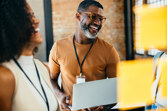 Smiling professionals collaborating in a creative office environment with positive energy - Powered by Adobe