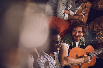 Friends hanging out with guitar and drinks in cozy bar setting