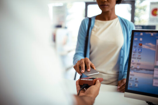 Woman making contactless payment at pharmacy counter