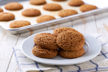 Oatmeal cookies are cooling after baking on a rack on a white table, selective focus.
