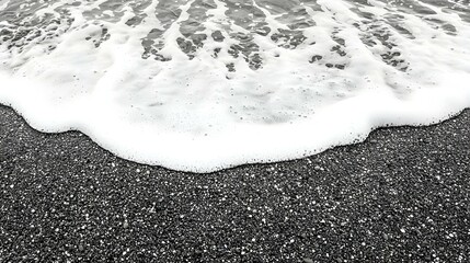 Obraz premium White ocean wave foam on a black pebble beach. Perfect for backgrounds, textures, and design projects.