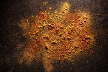 Bright spices scattered on black table, high contrast photo