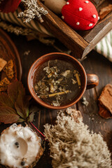 An idyllic autumn Thanksgiving scene on a wooden table with tea in a clay mug, leaves, twigs, pine cones. Hand-made romance decor and warm colors create a  comfortable atmosphere.
