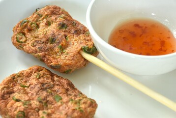grilled fish patty stabbing wooden stick on plate dipping sweet chili sauce 