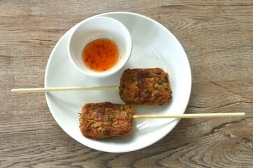 grilled fish patty stabbing wooden stick on plate dipping sweet chili sauce 