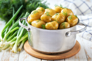 Tasty boiled new potatoes with fresh dill in a wooden table, selective focus.