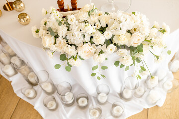 A beautiful wedding restaurant for a wedding. White decor for the bride and groom. Beauty wedding interior. Bouquet, candles and flowers in the hall.