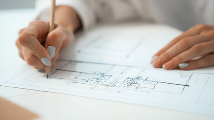 Closeup of professional caucasian female engineer hand drawing blueprint. Creative design and teamwork concept with blueprint and architectural equipments placed on table. Focus on hand. Immaculate.