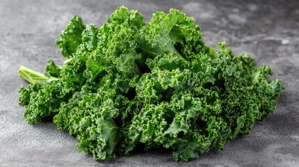 Fototapeta premium Fresh organic kale leaves piled on a textured grey surface showcasing vibrant green color and crisp texture perfect for healthy meals