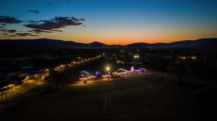 Fototapeta premium Twilight Gathering: A serene, twilight scene unfolds as a small town lights up under a colorful sunset, creating an ambiance of warmth, community, and a sense of belonging. 