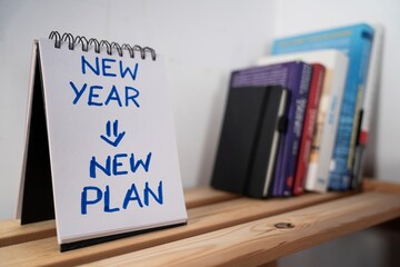 otwarty notes na półce z kartką na której zapisany jest tekst: New Year, New Plan © siwyk
