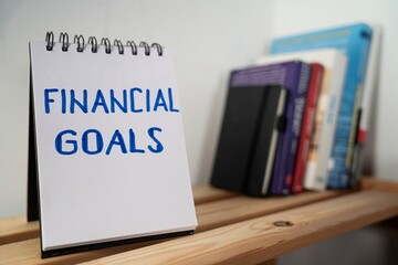 otwarty notes na półce z kartką na której zapisany jest tekst: Financial Goals  © siwyk