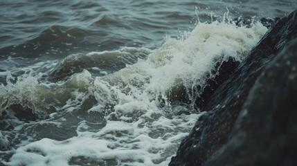 Stormy sea waves crashing violently against rugged rocky cliffs creating a dramatic coastal scene with foamy white spray and dark waters