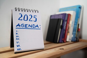 
otwarty notes na półce z kartką na której zapisany jest tekst: 2025 Agenda oraz poniżej...
