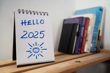otwarty notes na półce z kartką na której zapisany jest tekst: Hello 2025 © siwyk