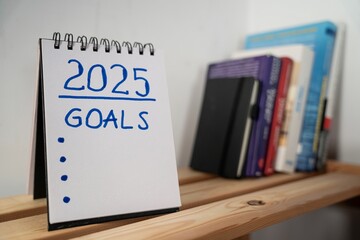 otwarty notes na półce z kartką na której zapisany jest 2025, goals oraz wykropkowane wolne miejsce do zapisania © siwyk