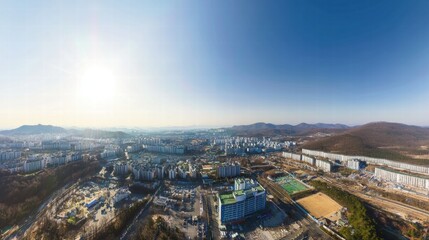 Obraz premium Panoramic Cityscape: A breathtaking panoramic view of a modern city nestled amidst rolling hills, bathed in the warm glow of a bright sunny day.