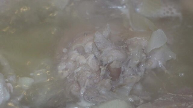 boiling broth from a bone, boiling soup with meat close-up, a bone is boiled in broth