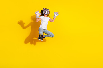 Obraz premium Girl in a white t-shirt wearing a cat mask playfully posing against a vibrant yellow background