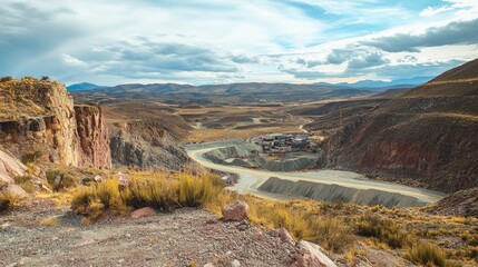 Obraz premium Vast Landscape of an Abandoned Silver Mine Surrounded by Mountains and Open Sky Under a Dramatic Cloudscape