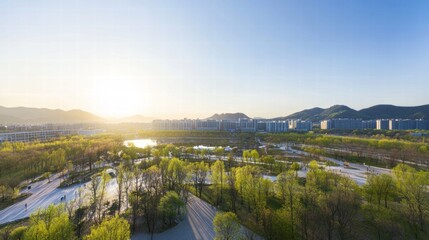 Obraz premium Sunrise Cityscape: Serene aerial view of a modern city nestled amidst lush greenery and a tranquil lake, bathed in the warm glow of sunrise. The image evokes a sense of peace and urban harmony. 