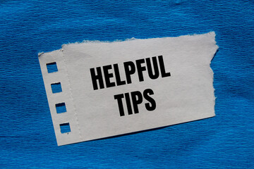 Helpful tips message written on ripped torn paper piece with blue background. Conceptual helpful...