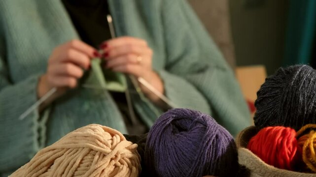 A young woman's hands carefully knitting with green yarn in a close-up video. A relaxing moment of craftsmanship and creativity highlighted in detail