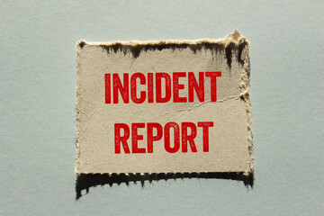 Incident report message written on ripped torn paper piece on gray background. Conceptual incident...