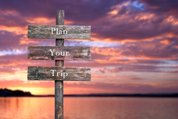 plan your trip text quote on wooden signpost outdoors by the lake during red dramatic sunset.