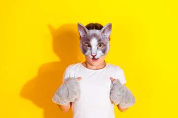 Girl wearing a cat mask smiling against vibrant yellow background in casual fashion