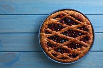 Delicious currant pie and fresh berries on blue wooden table, top view. Space for text