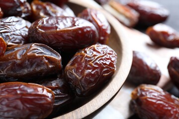 Many tasty dried dates in bowl on table, closeup