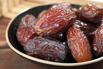 Many tasty dried dates in bowl on table, closeup