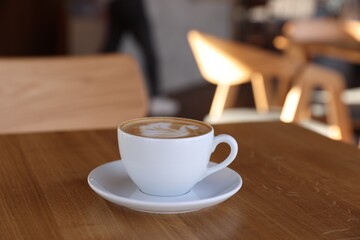 Cup of aromatic coffee on wooden table in cafe