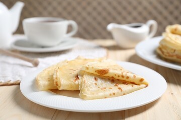 Tasty crepes on wooden table, closeup view