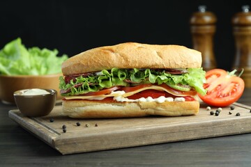 Delicious baguette sandwich with salami and cheese on grey wooden table