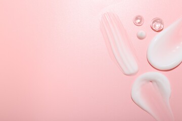 Cream and gel samples on pink background, top view. Space for text