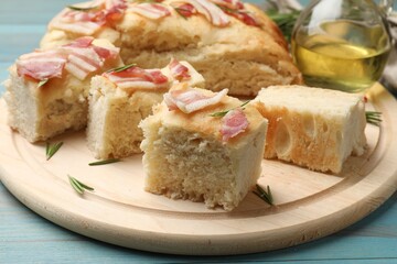 Pieces of delicious focaccia bread with bacon served on blue wooden table, closeup