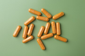Many turmeric capsules on light green background, flat lay