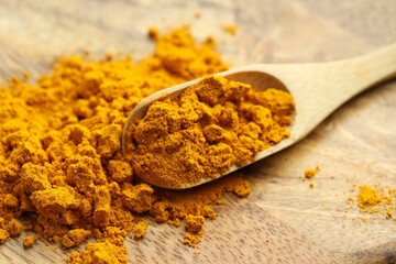 Turmeric powder and spoon on table, closeup