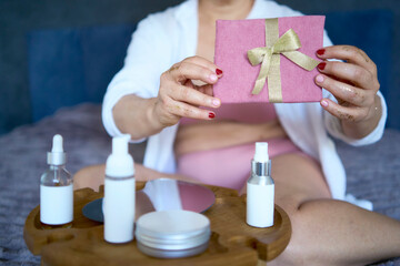 a senior woman in underwear with gold glitter on her face and hands holding a gift certificate