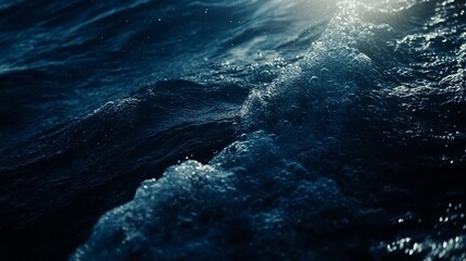 Close-up of dark blue ocean waves with whitecaps and sunlight.