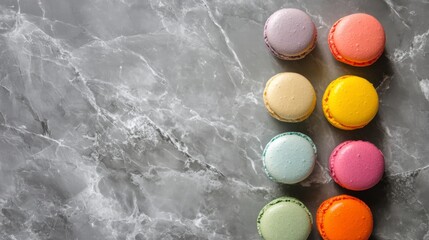 A Rainbow of Macarons: A vibrant and delectable array of colorful macarons arranged in a diagonal line on a gray marble background, leaving space for your text or design.