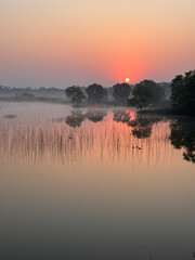 A beautiful sunset over a lake with a reflection of the sun in the water