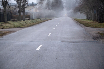 Street with dividing line in village. Misty morning in early winter. Latvia, Jelgava.