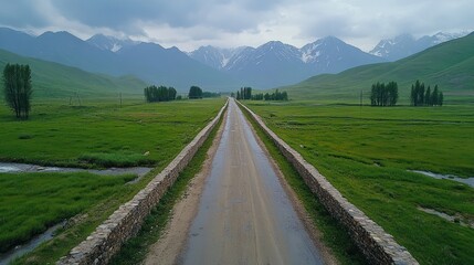 Empty rural road bridge, green valley, mountains, cloudy sky.