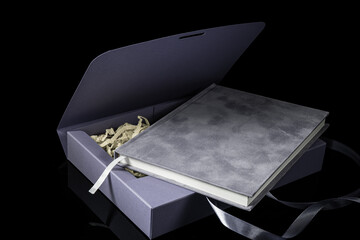 Best gift for men. Man gift concept. Purple notebook with purple gift box on black background. Copy space. Valentine's day, wedding, birthday and special occasion gift concept. Copy space for text.