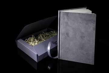 Best gift for men. Man gift concept. Purple notebook with purple gift box on black background. Copy space. Valentine's day, wedding, birthday and special occasion gift concept. Copy space for text.